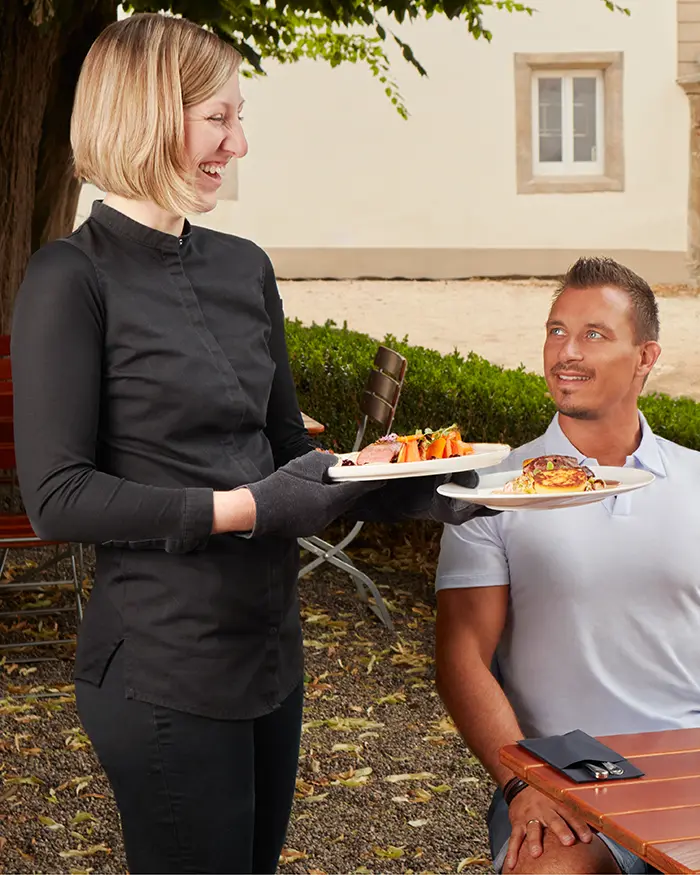 friendly Waitress serving dishes to a table
