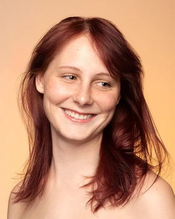 Woman with dark red hair smiling and looking away