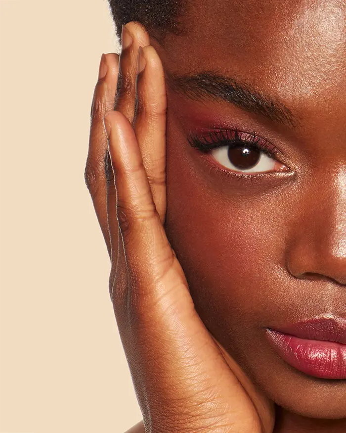 close up of a black womans face with a lifted face and purple eye shadow