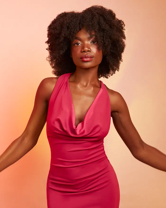 Black woman with natural afro curls wearing a pink dress