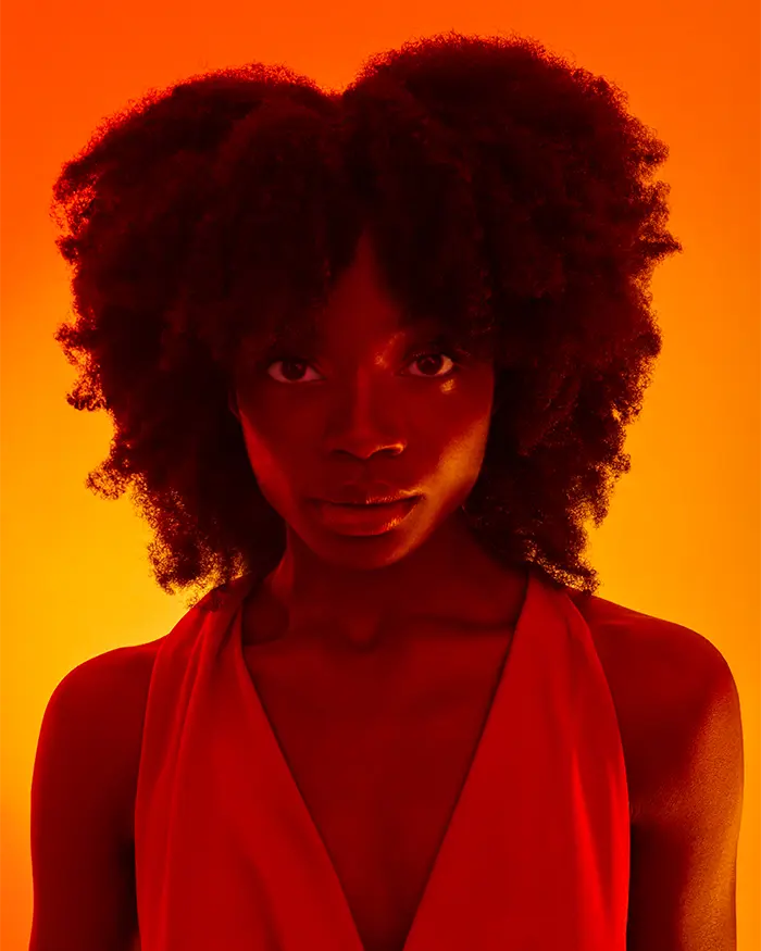 Black woman with natural afro curls in a orange sunset light