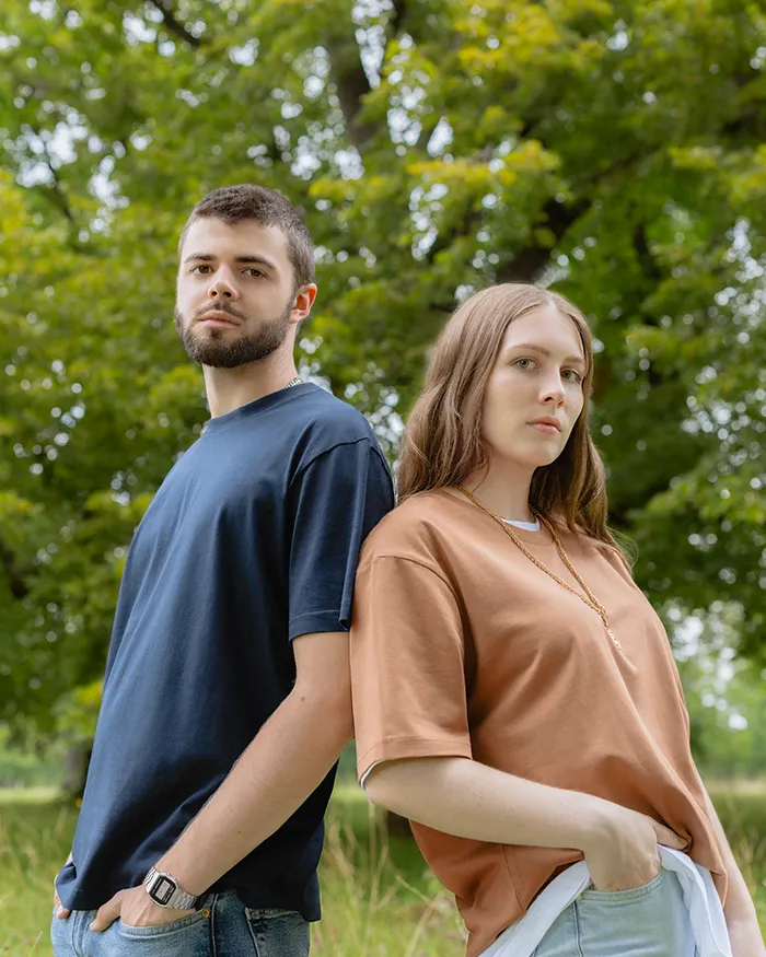 man and woman leaning on eachother wearing streetwear in a field