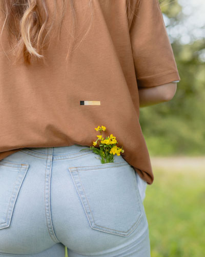 closeup shot of a womans back with yellow flowers in her back pocket